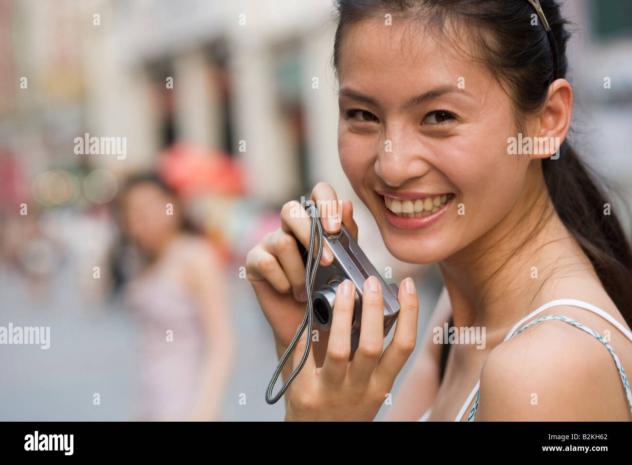 Close-up of a young woman holding a camera and smiling Stock Photo - Alamy