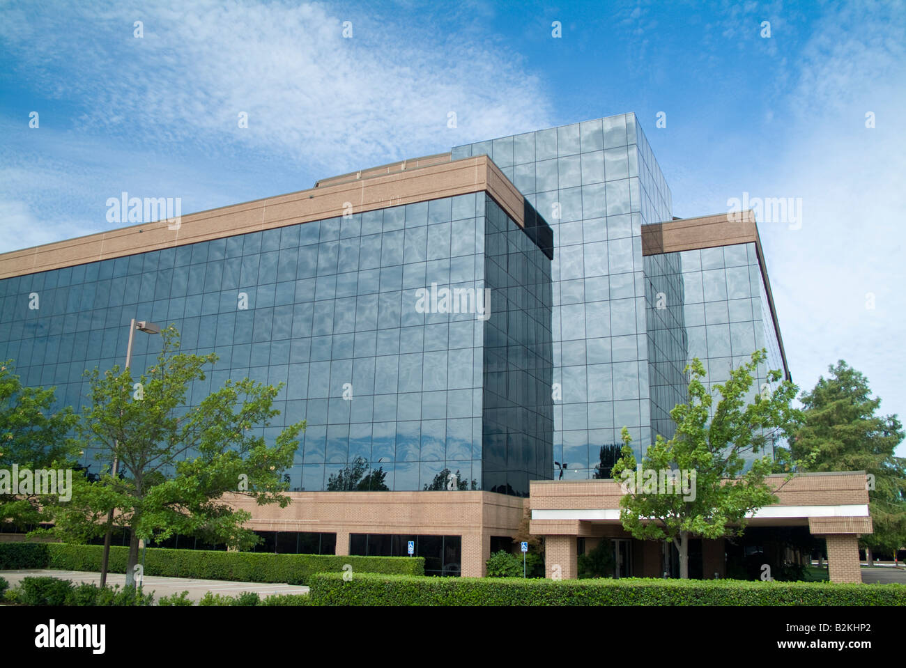 A building with a glass exterior reflecting the sky and clouds above ...