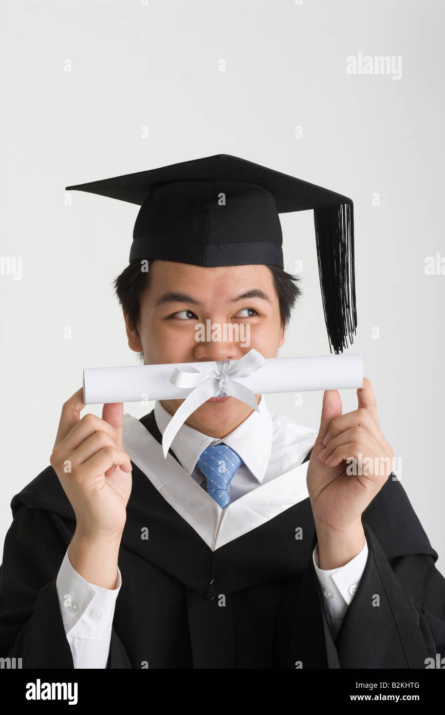 Young male graduate holding a diploma in front of his face Stock Photo ...