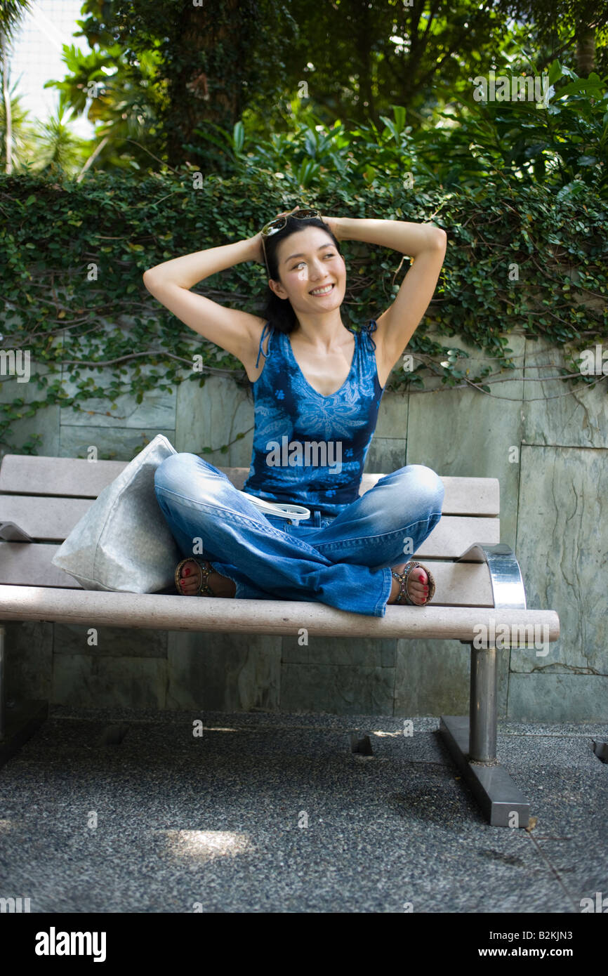 Young woman sitting on a bench in a park and smiling Stock Photo - Alamy
