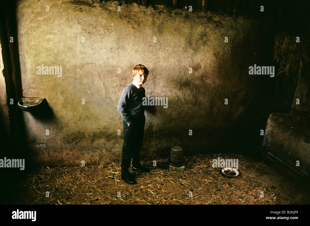 RURAL NORTHERN IRELAND GINGER HAIRED BOY WEARING HIS SCHOOL UNIFORM STANDING INSIDE BUILDING WHERE CHICKENS ARE FED KEPT AT HOME Stock Photo
