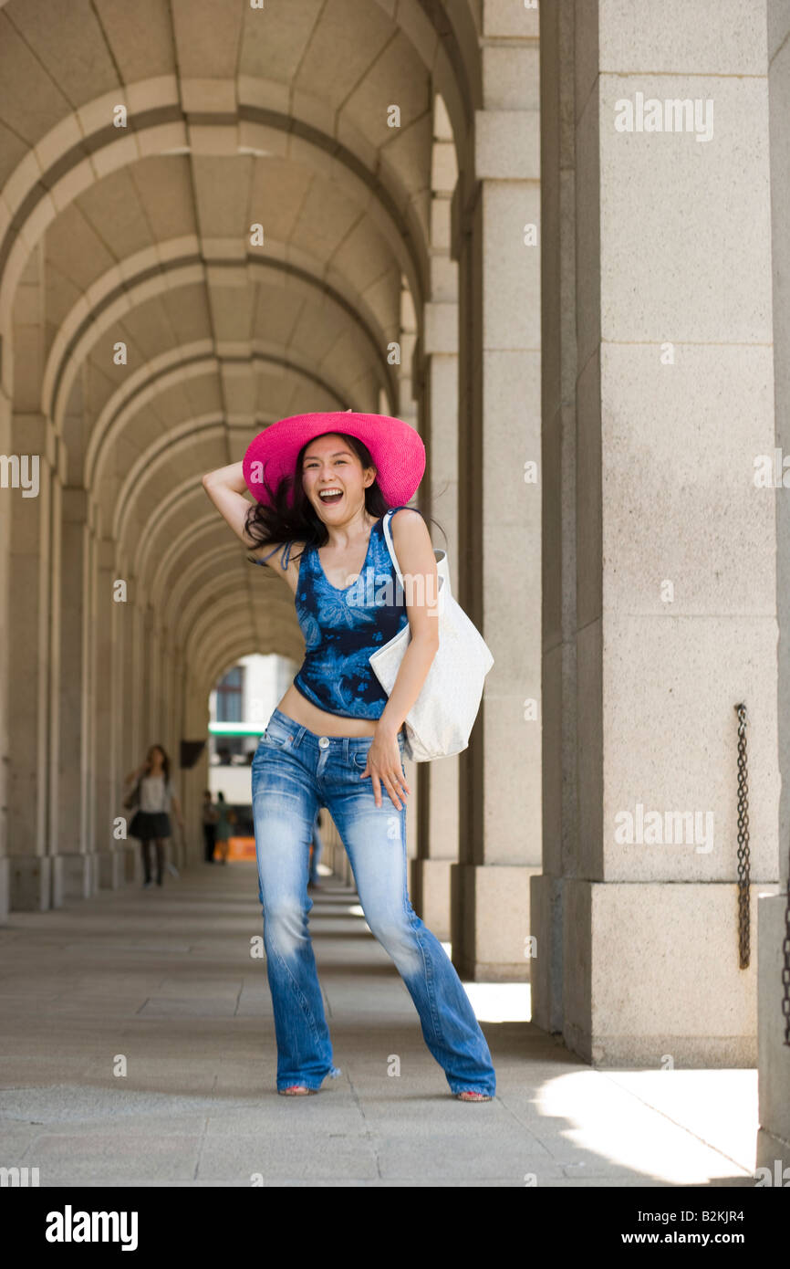 Portrait of a young woman holding her sun hat and laughing Stock Photo ...