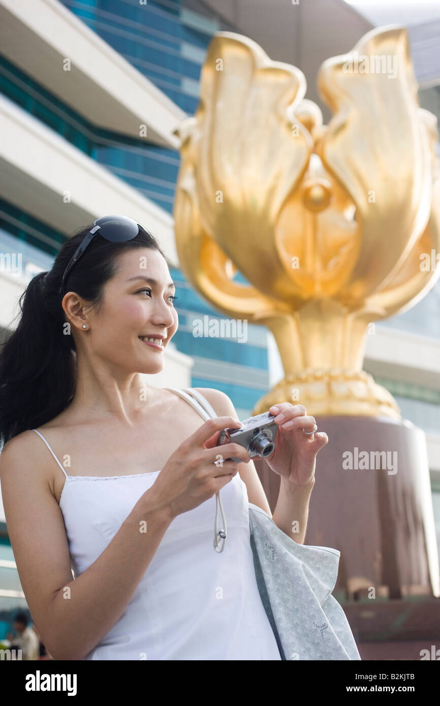 Young woman holding a digital camera and smiling Stock Photo - Alamy