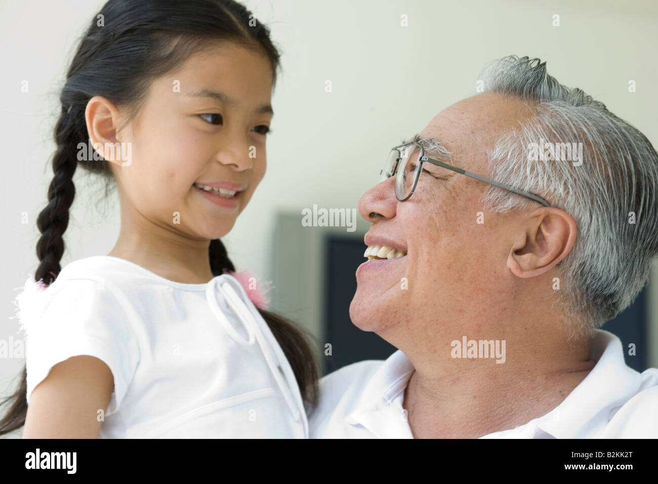 Close-up of a senior man and his granddaughter smiling at each other Stock Photo