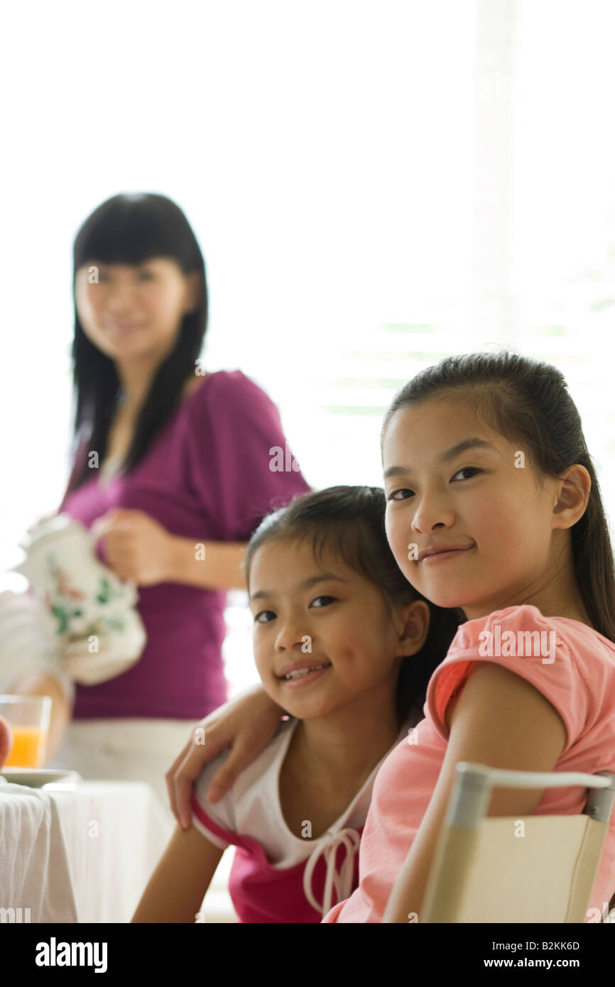 Portrait of a girl sitting with her sister at a dining table and ...