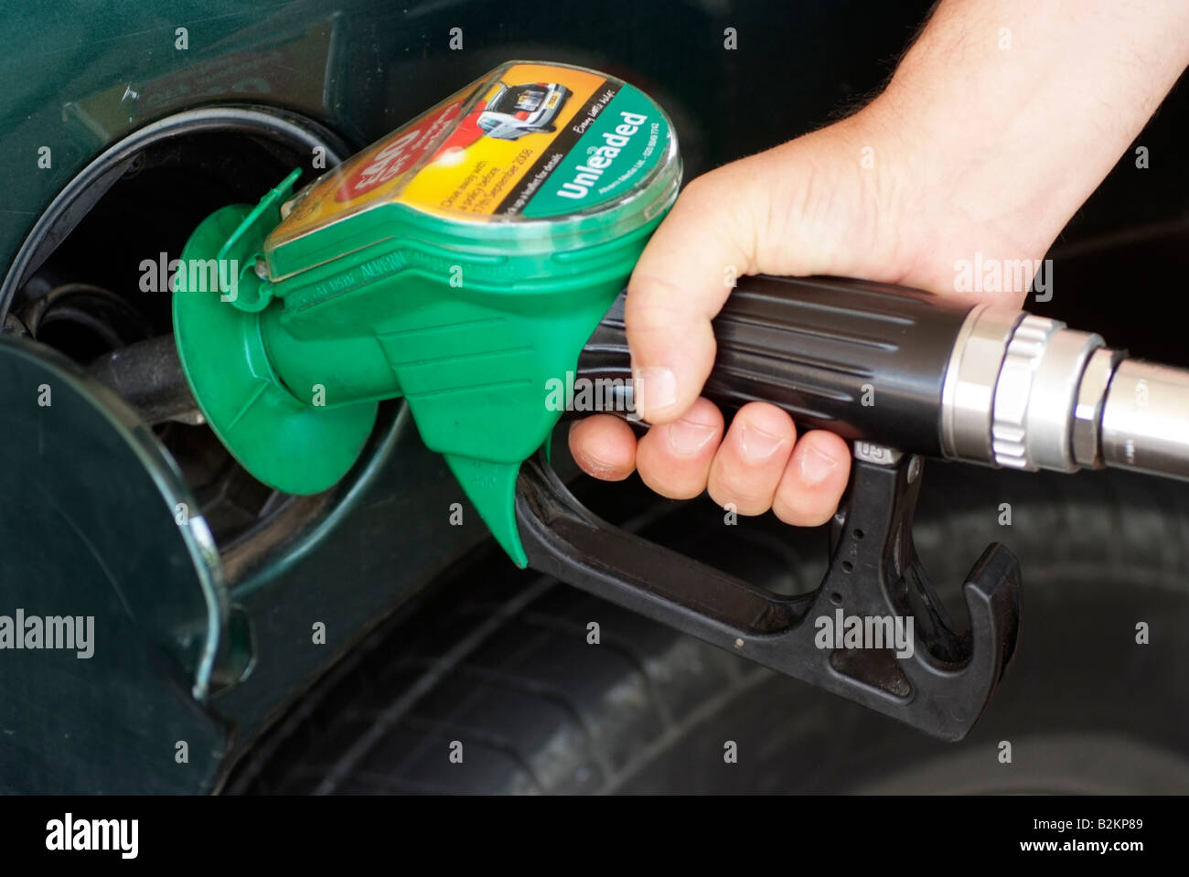 Filling car petrol tank with unleaded fuel at a Tesco filling station On the pump an advert promoting car insurance Stock Photo