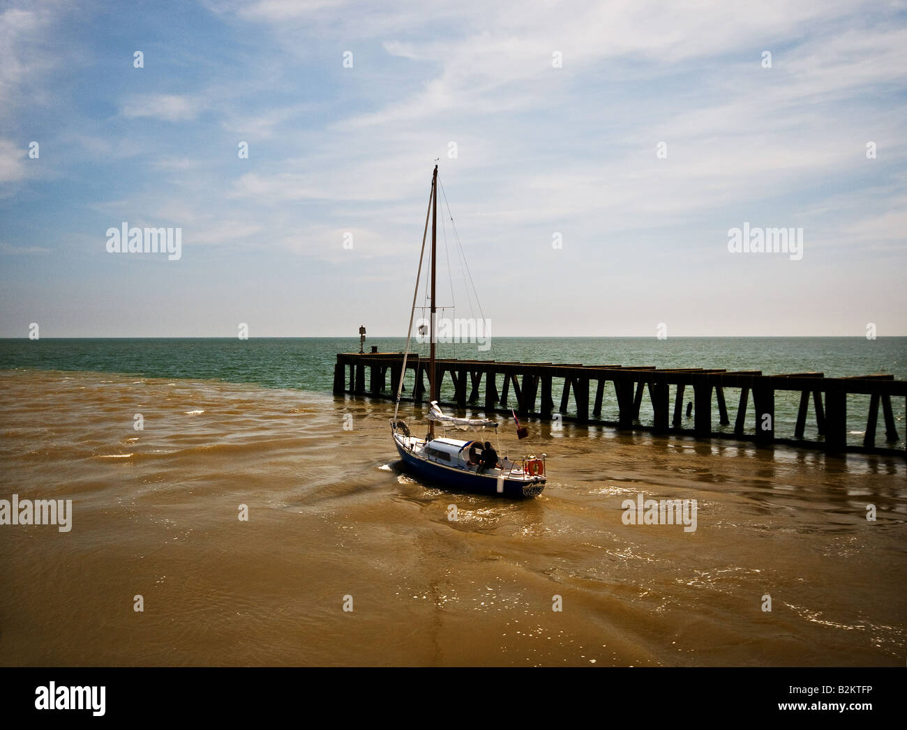 A sailboat leaving the River Blythe at Southwold in Suffolk. Stock Photo
