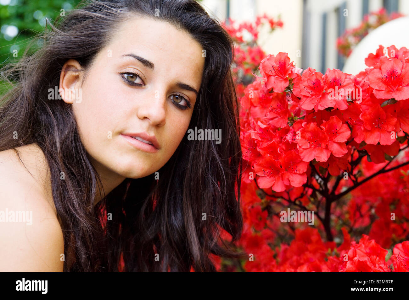 Young pretty girl close to red flowers Stock Photo