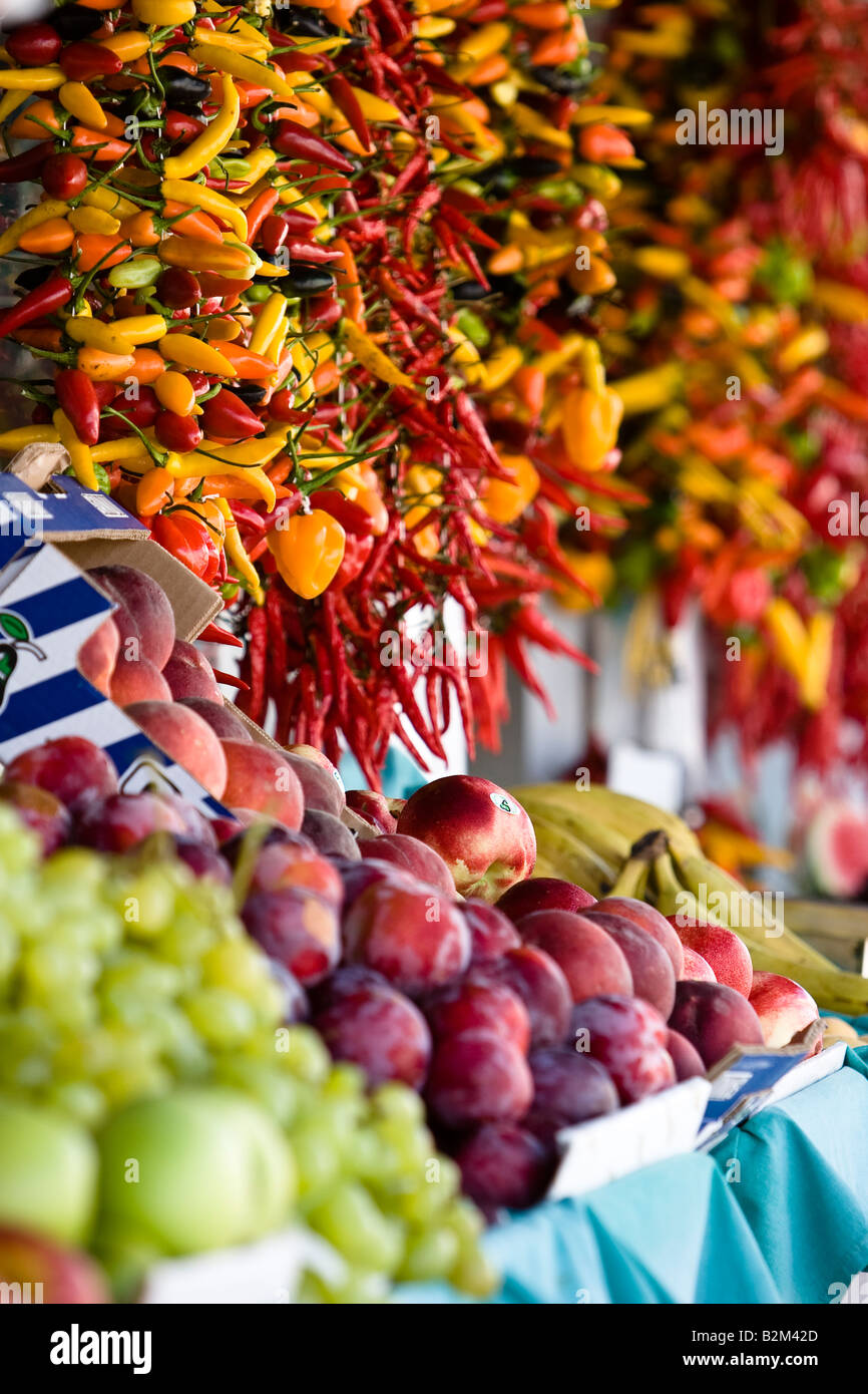 Red yellow and green pepper hanging in baskets in a shop, in Cala