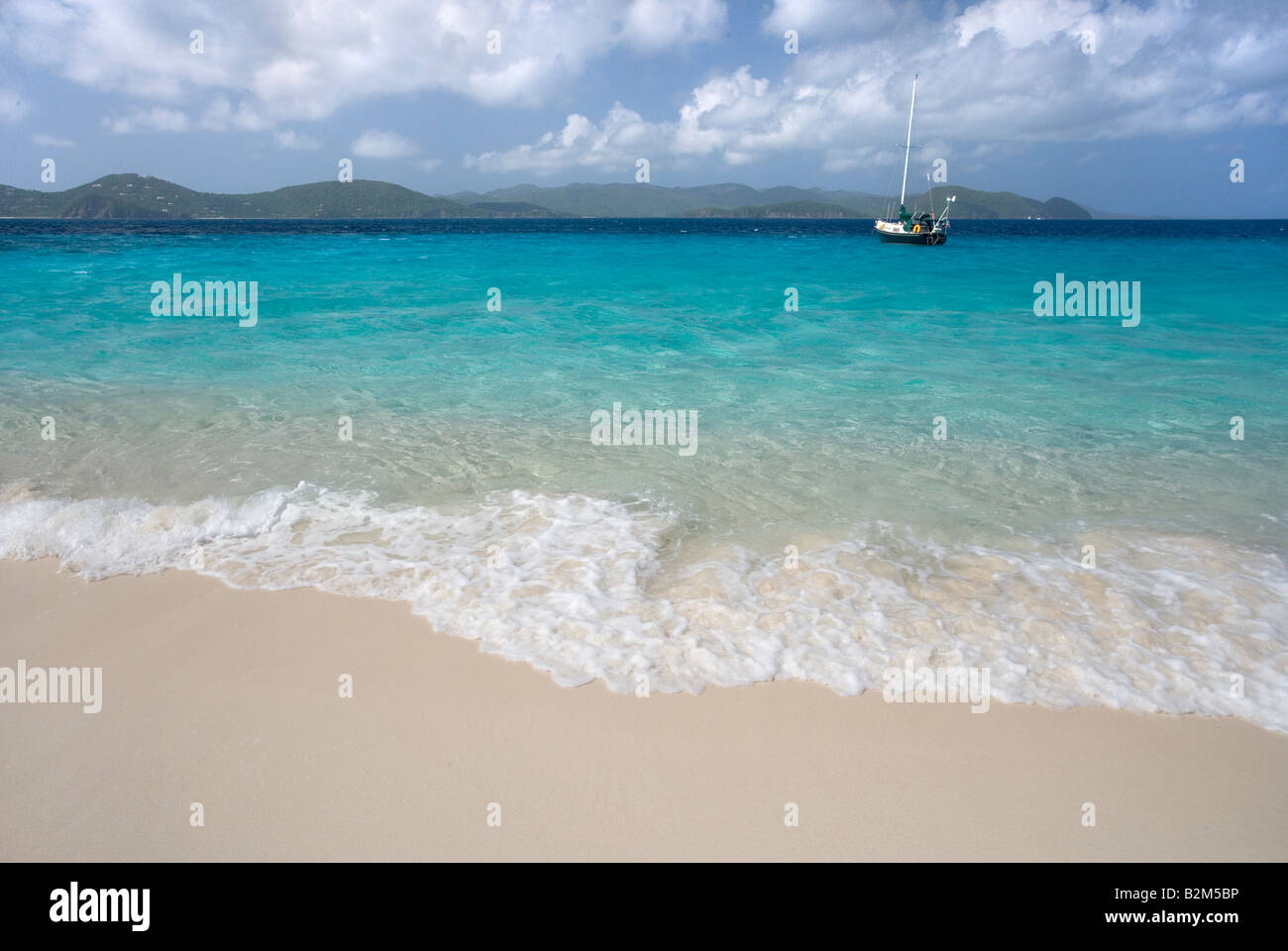 A cruising sailboat anchored next to Sandy Cay in the British Virgin Islands Tortola and St John is visible in the background Stock Photo