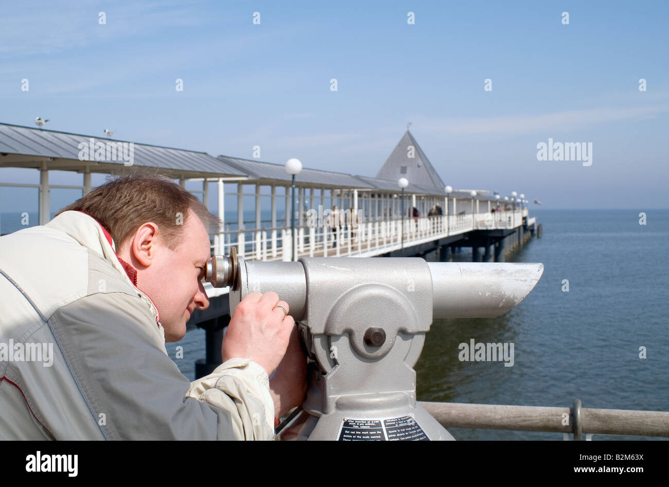 Man looking through binoculars / Pier Heringsdorf, Usedom, Germany Stock Photo