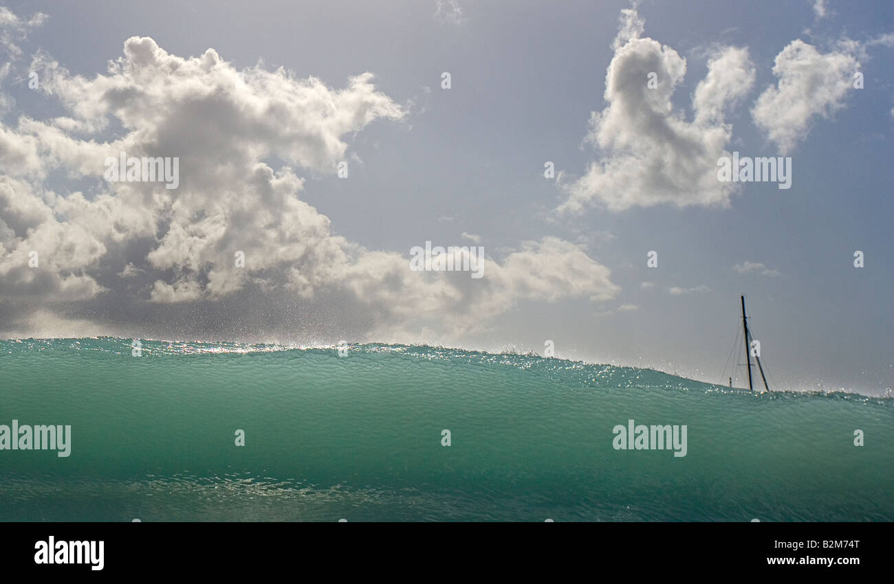 A sailboat is almost completely obscured by a wave breaking on a beach Stock Photo