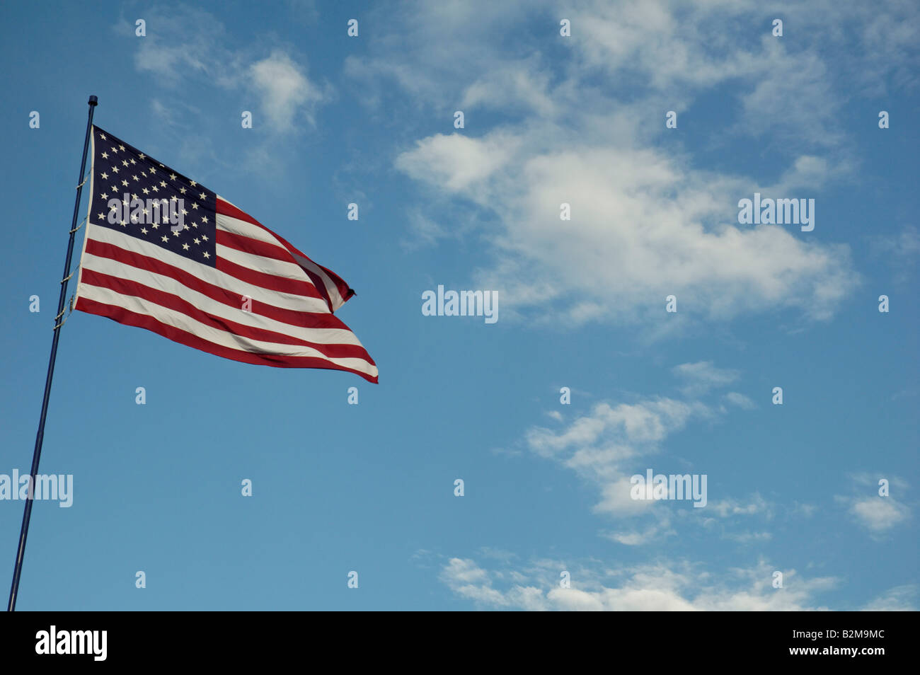United states of America flag blowing in the wind with clouds and blue sky background Stock Photo
