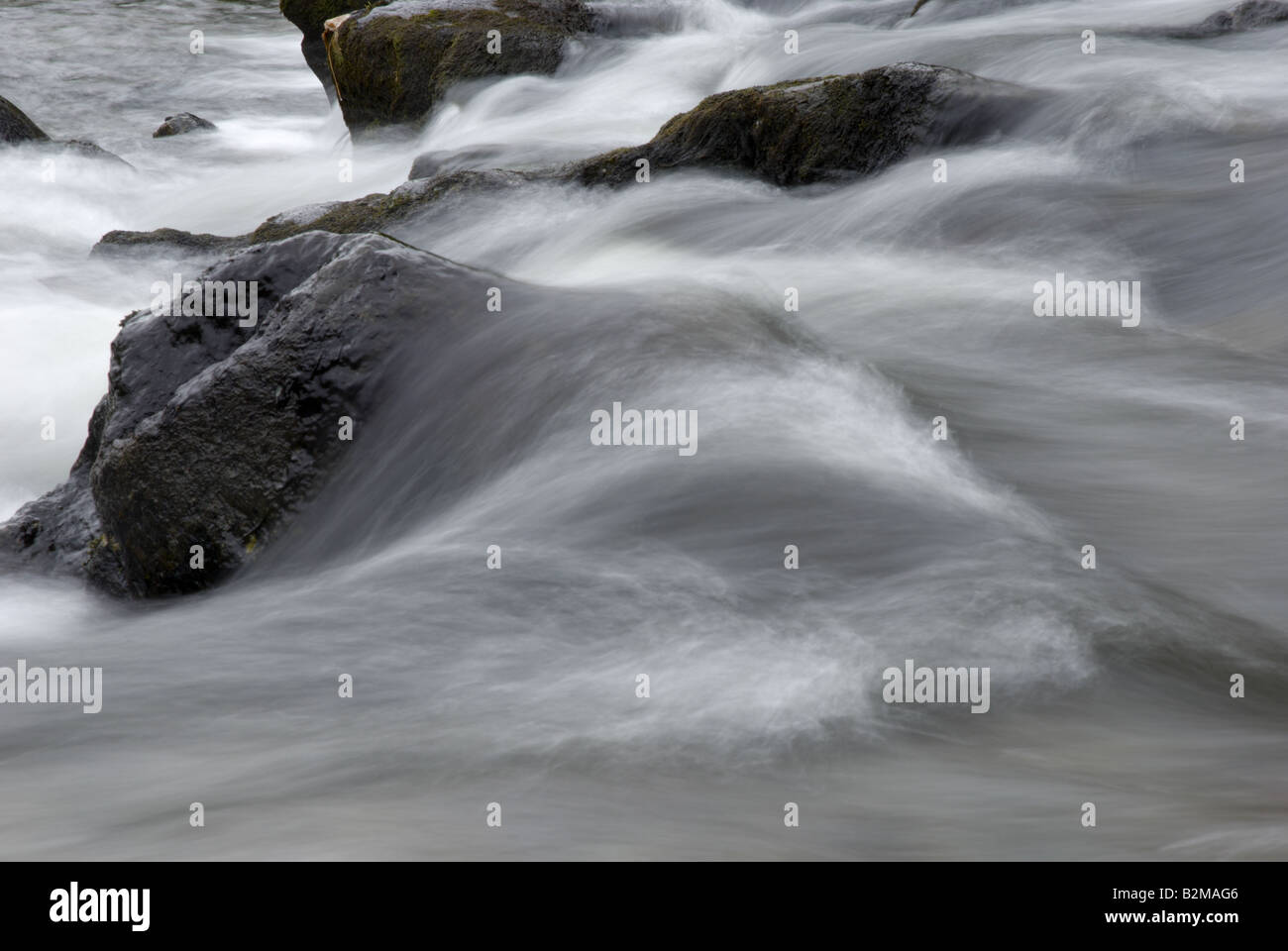 Fast Moving River Water flowing over stones in a series of rapids Stock Photo