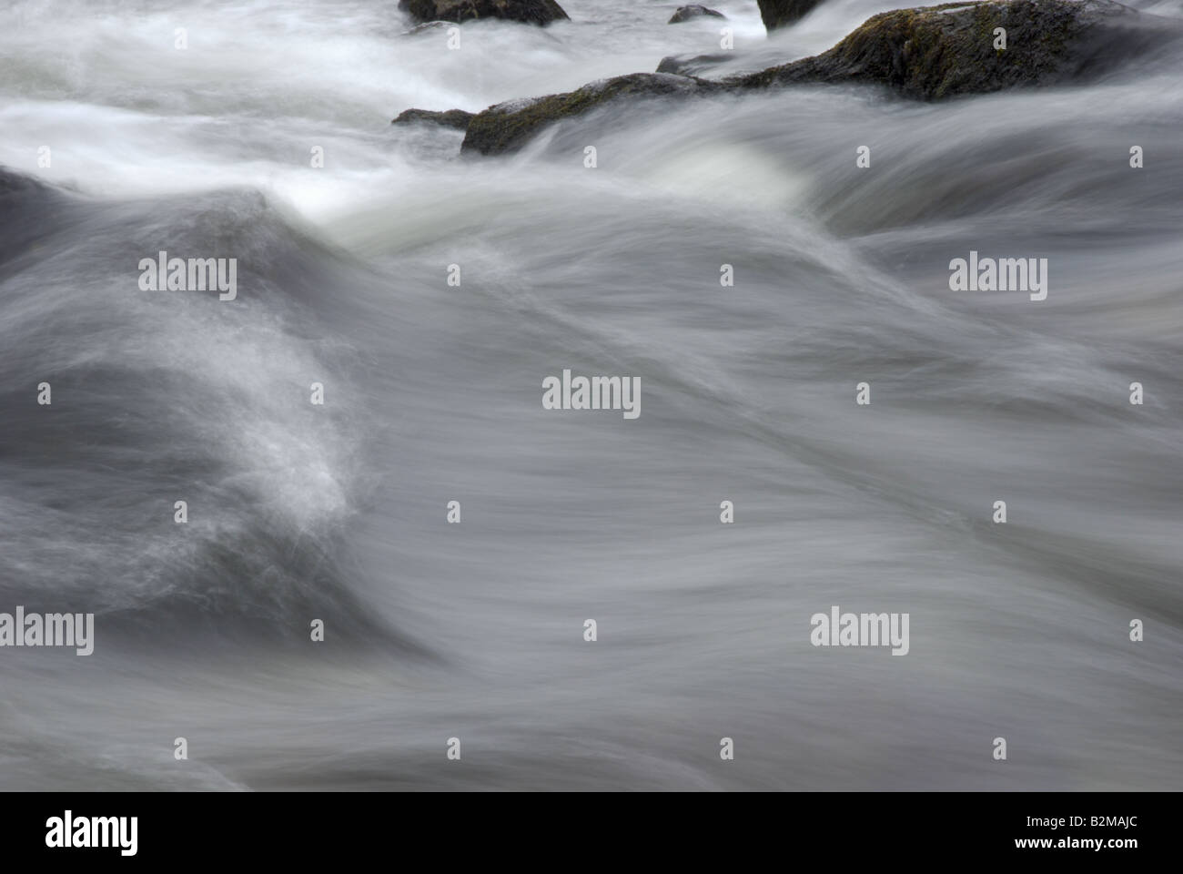 Fast Moving River Water flowing over stones in a series of rapids Stock Photo