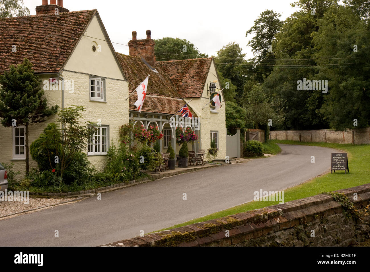 An English village inn with flags fluttering in the gentle breeze on a summer day in rural Oxfordshire. Stock Photo