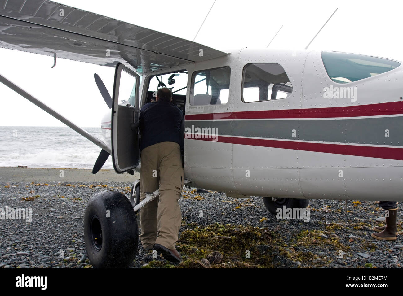 Pilot checking his airplane on a beach at Katmai Park and Preserve, Alaska Stock Photo