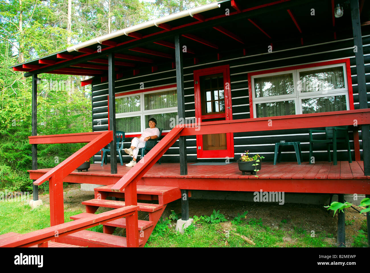 Woman sitting on a deck of log cabin Stock Photo - Alamy