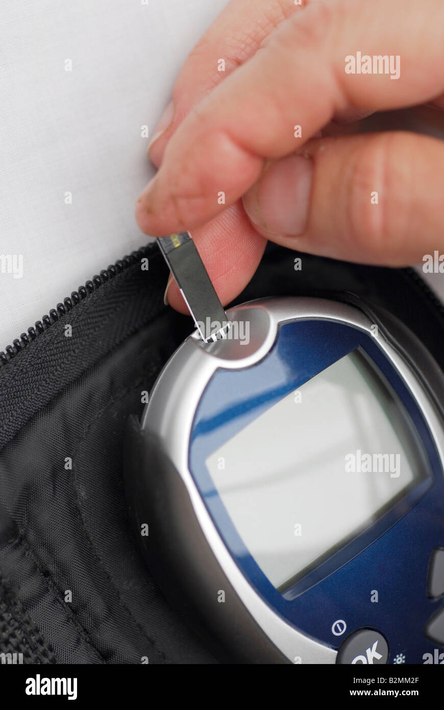 Diabetic inserting blood test strip into digital blood glucose meter