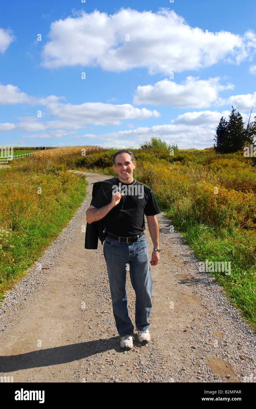 Smiling man walking on a country road Stock Photo Alamy