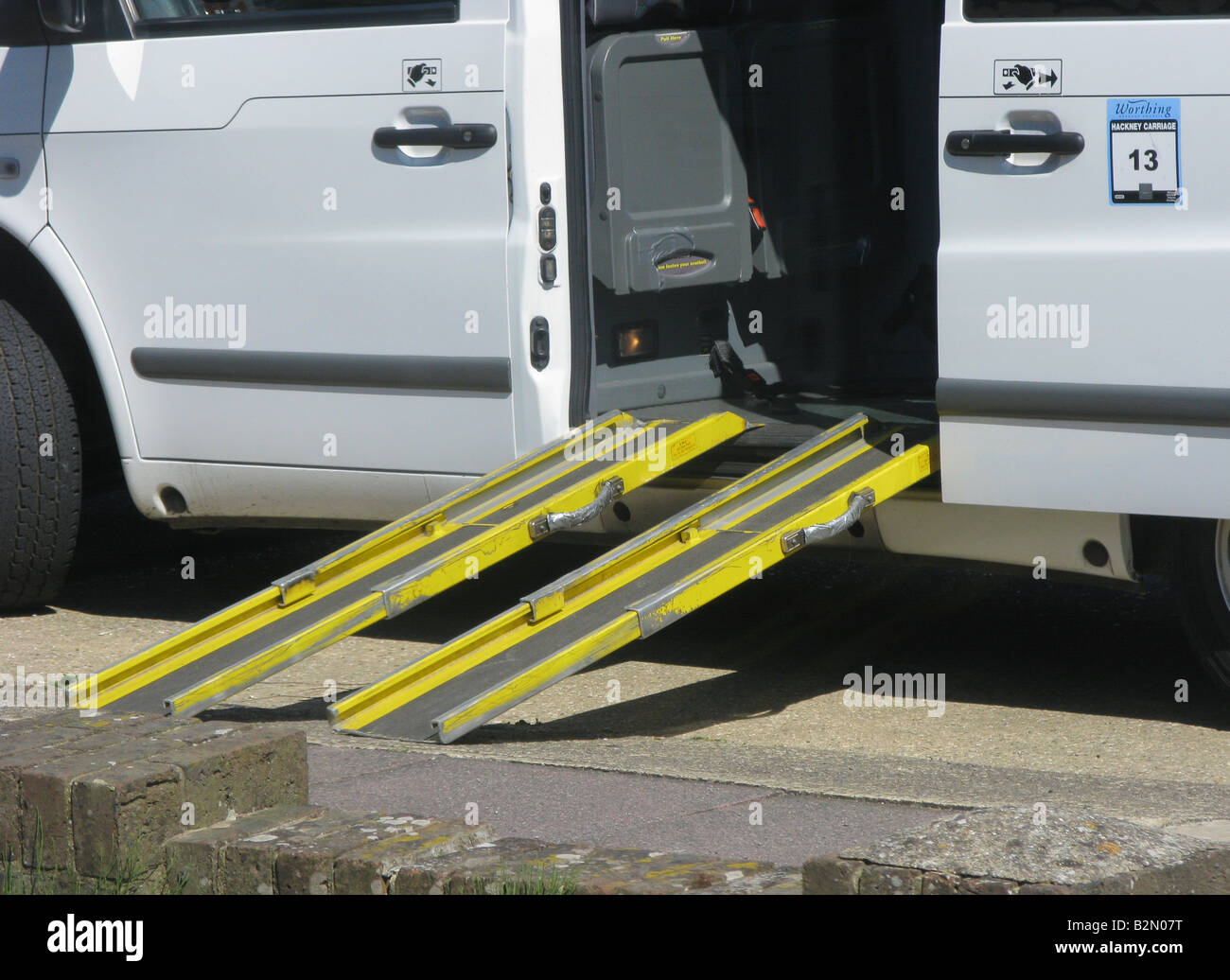 a two piece slip resistant ramp in place from the road to a wheelchair friendly taxi for the disabled enabling mobility Stock Photo