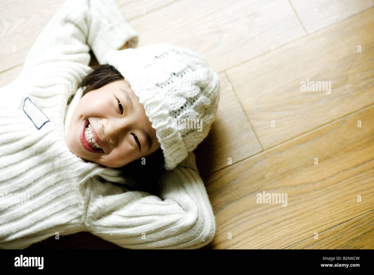 Portrait of a smiling girl lying on hardwood flooring Stock Photo Alamy