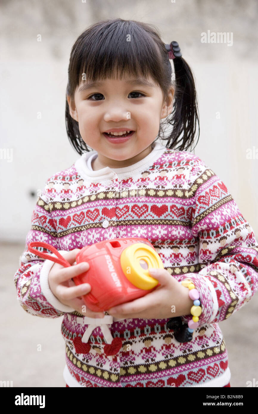 Portrait of a girl holding a toy camera and smiling Stock Photo