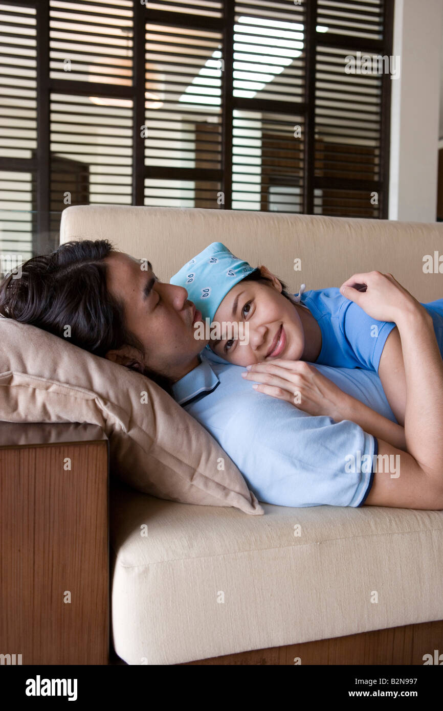 Side profile of a young man lying on a couch with a young woman Stock ...