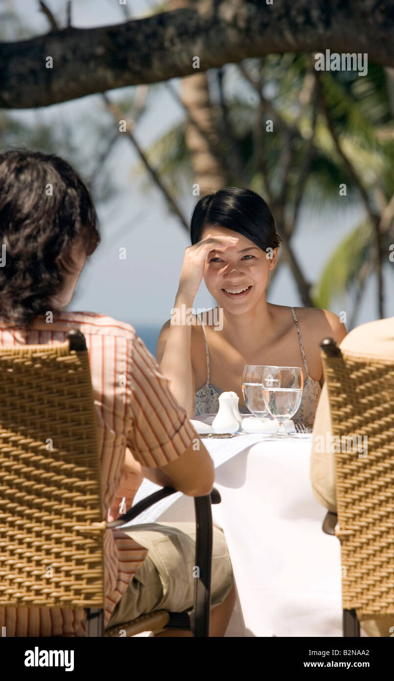 Young woman sitting at dining table with her friends and smiling, Phuket, Thailand Stock Photo