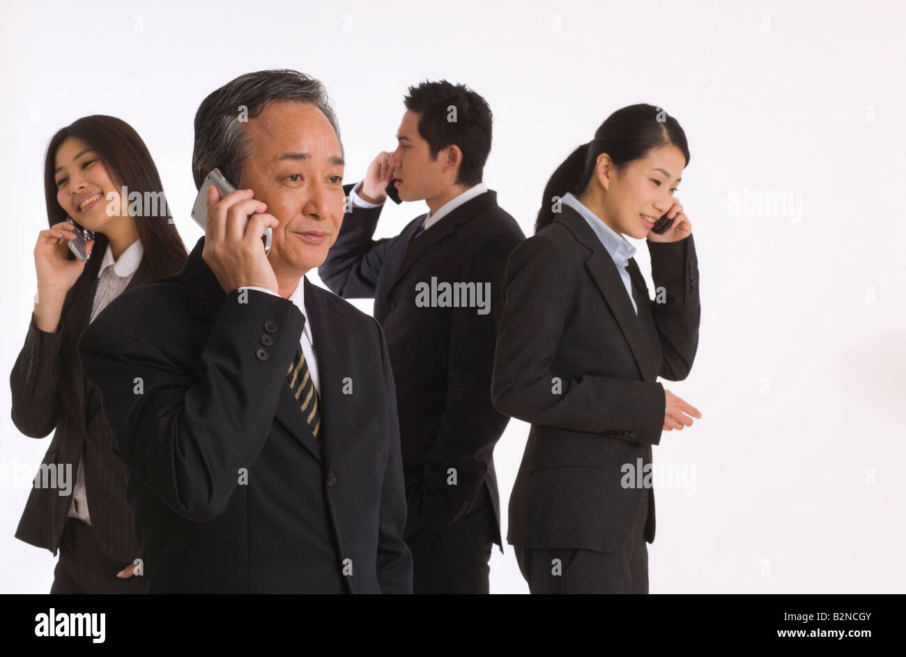 Four business executives using their mobile phones Stock Photo - Alamy