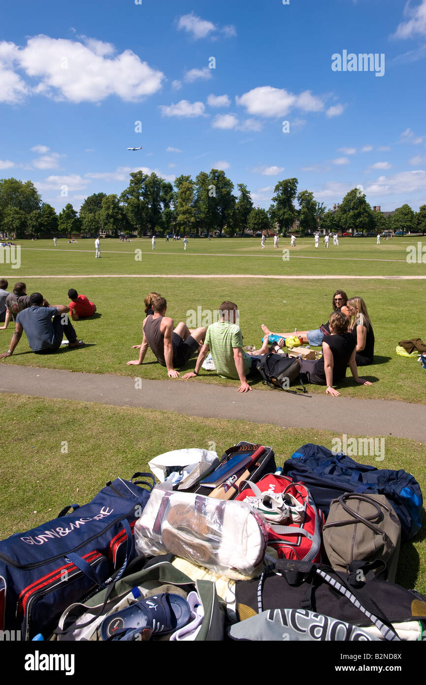 People relax and watch a game of cricket on warm summer afternoon The Green Richmond TW10 Surrey United Kingdom Stock Photo