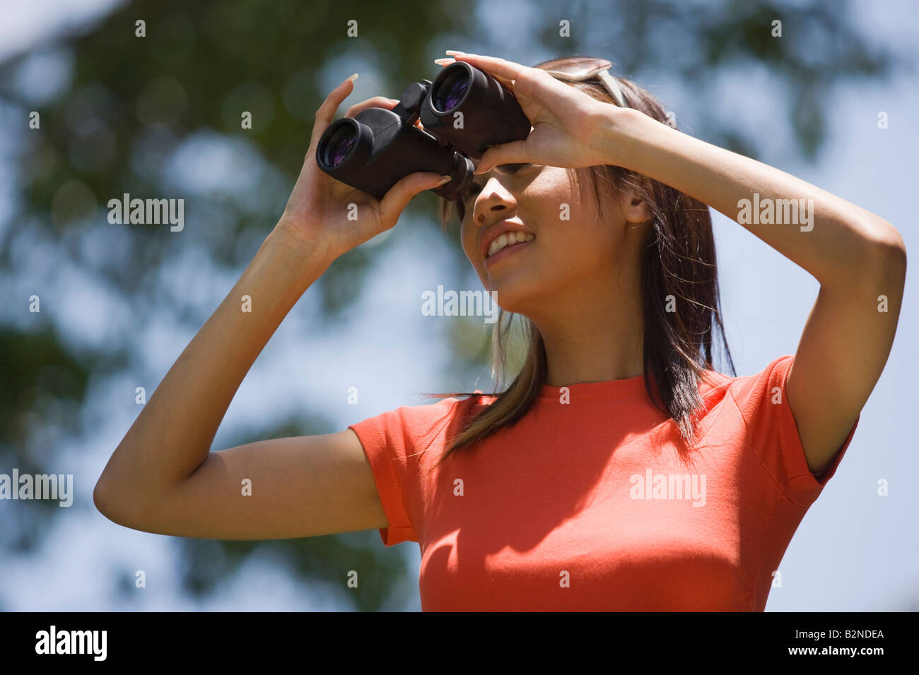 Young woman looking through binoculars, Singapore Stock Photo Alamy