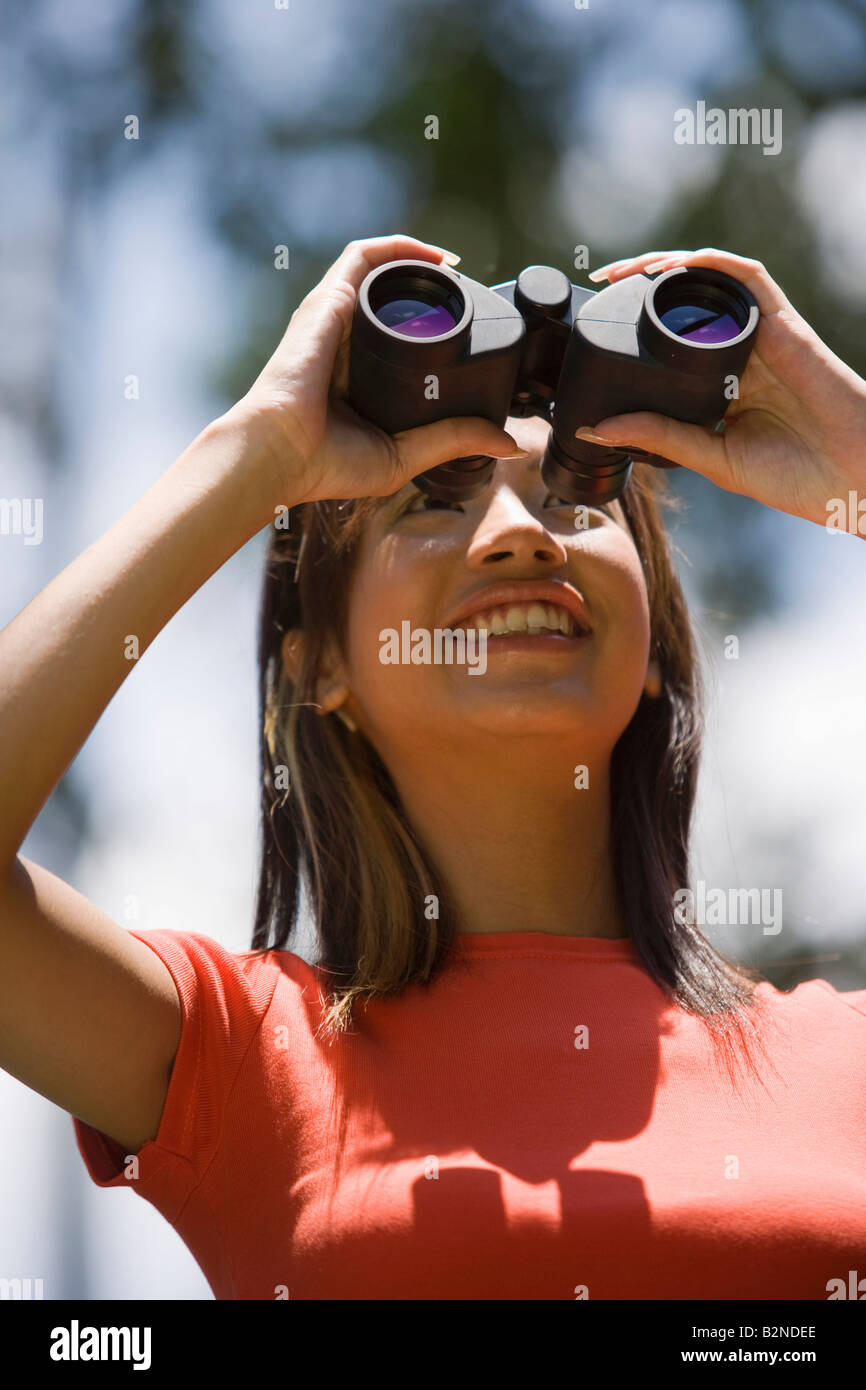 Young woman looking through binoculars, Singapore Stock Photo Alamy
