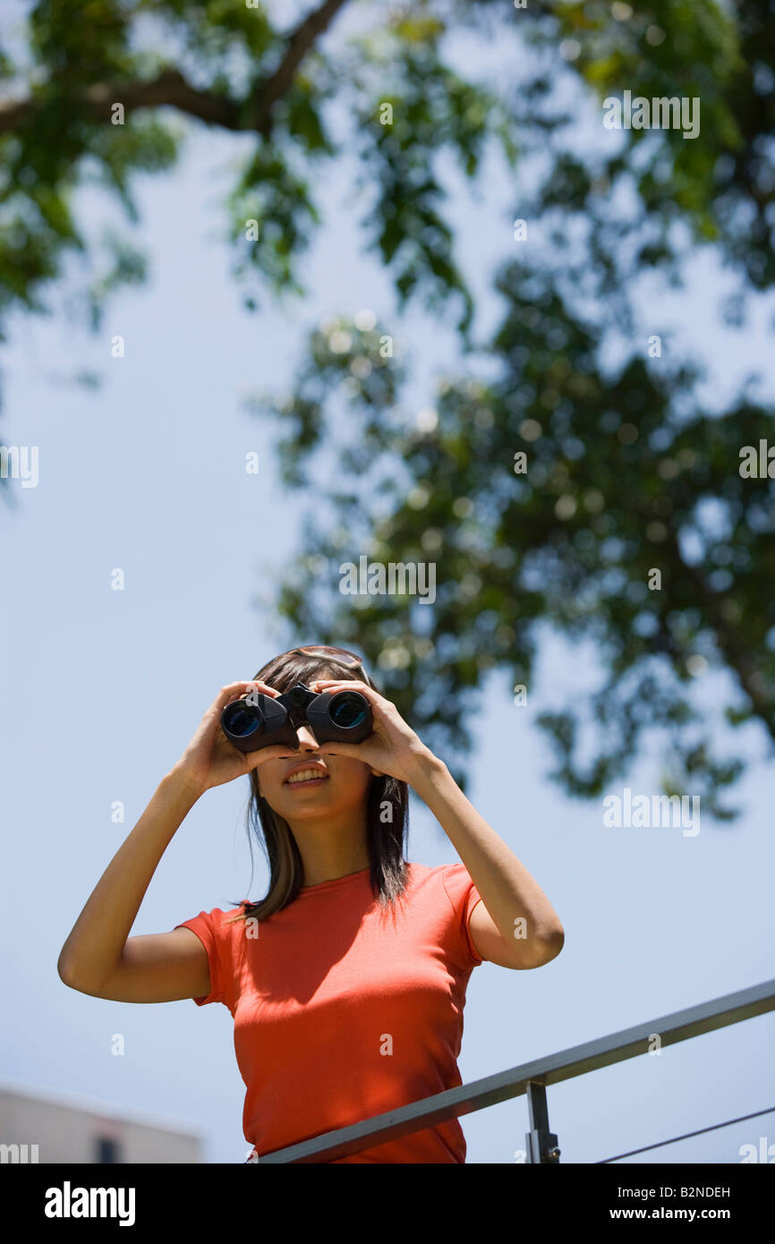 Young woman looking through binoculars, Singapore Stock Photo Alamy