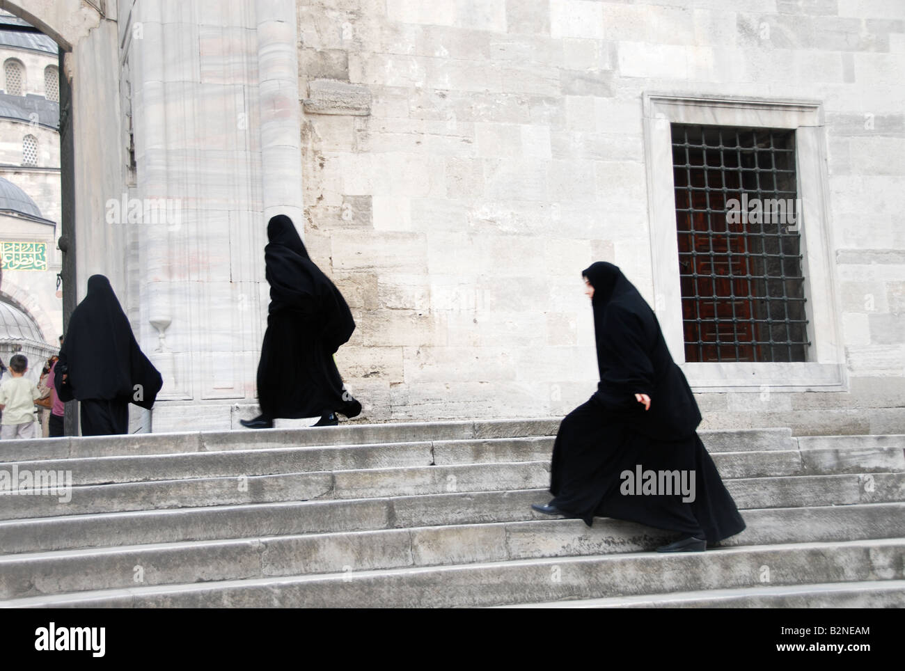 Muslim woman entering a mosque, they are wearing a burka Stock Photo