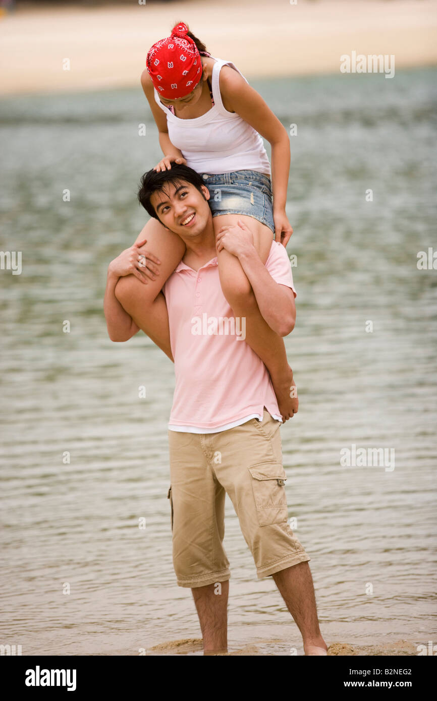 Young woman sitting on a young man's shoulders on the beach Stock Photo ...