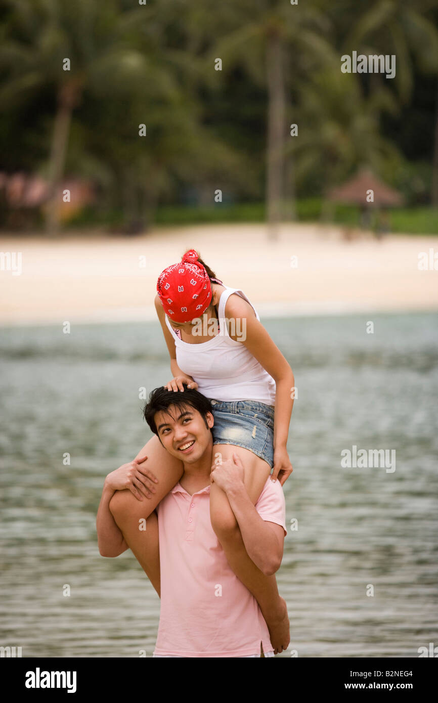 Young woman sitting on a young man's shoulders on the beach Stock Photo ...