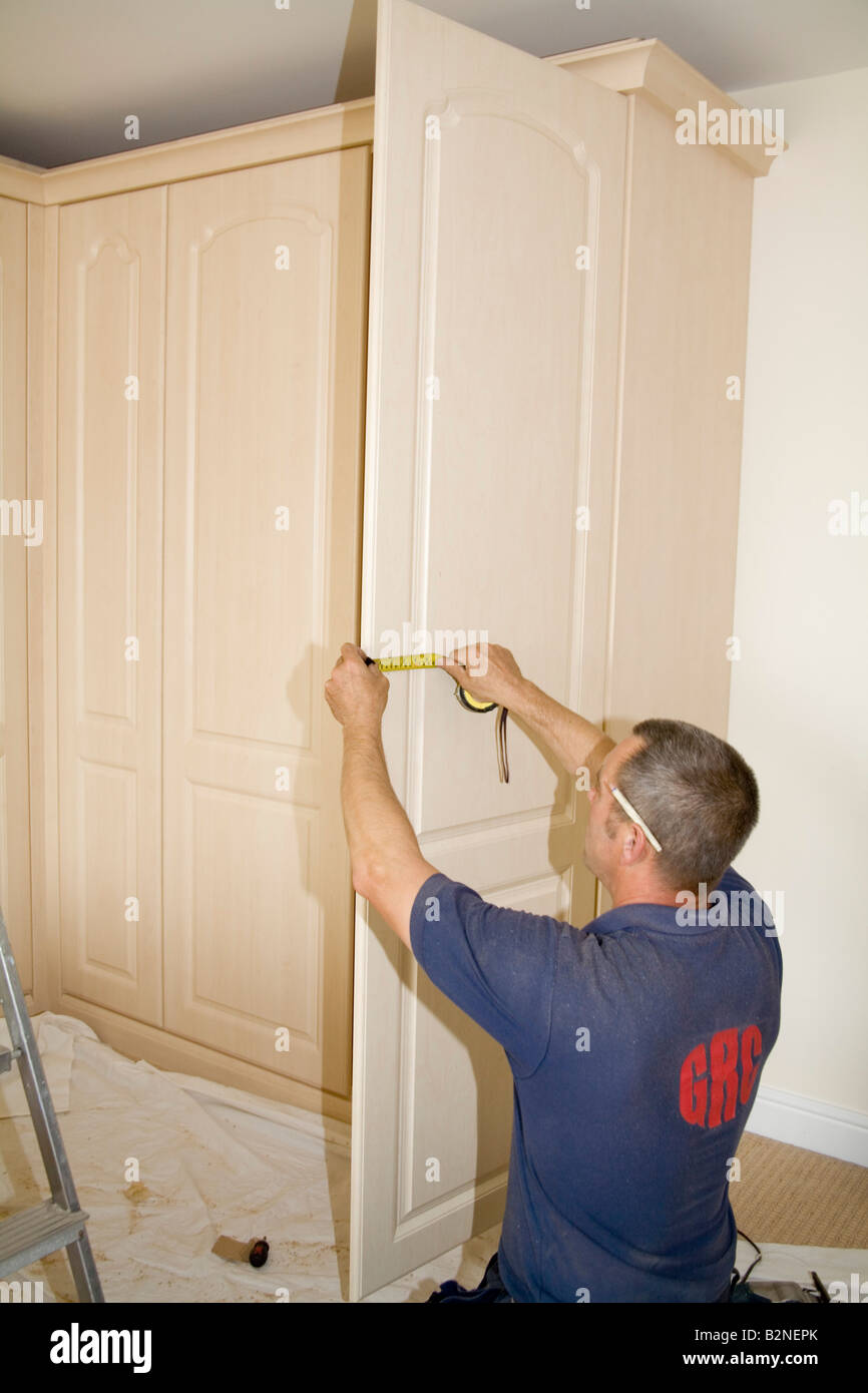 Close Up Of A Carpenter Fitting Wardrobes Using A Steel Tape