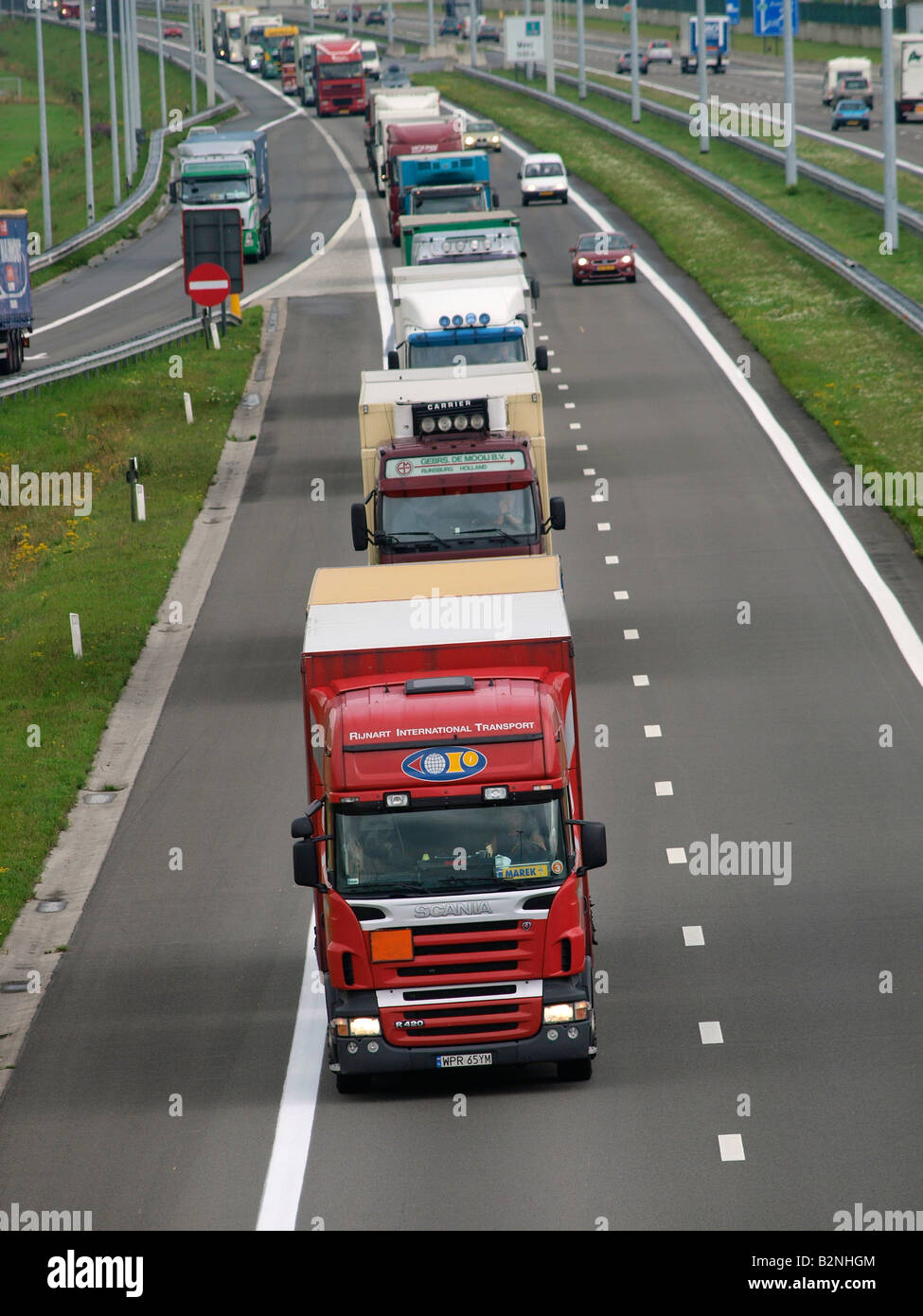 Long line of trucks driving north towards Holland on the E19 near the border at Hazeldonk Belgium Stock Photo