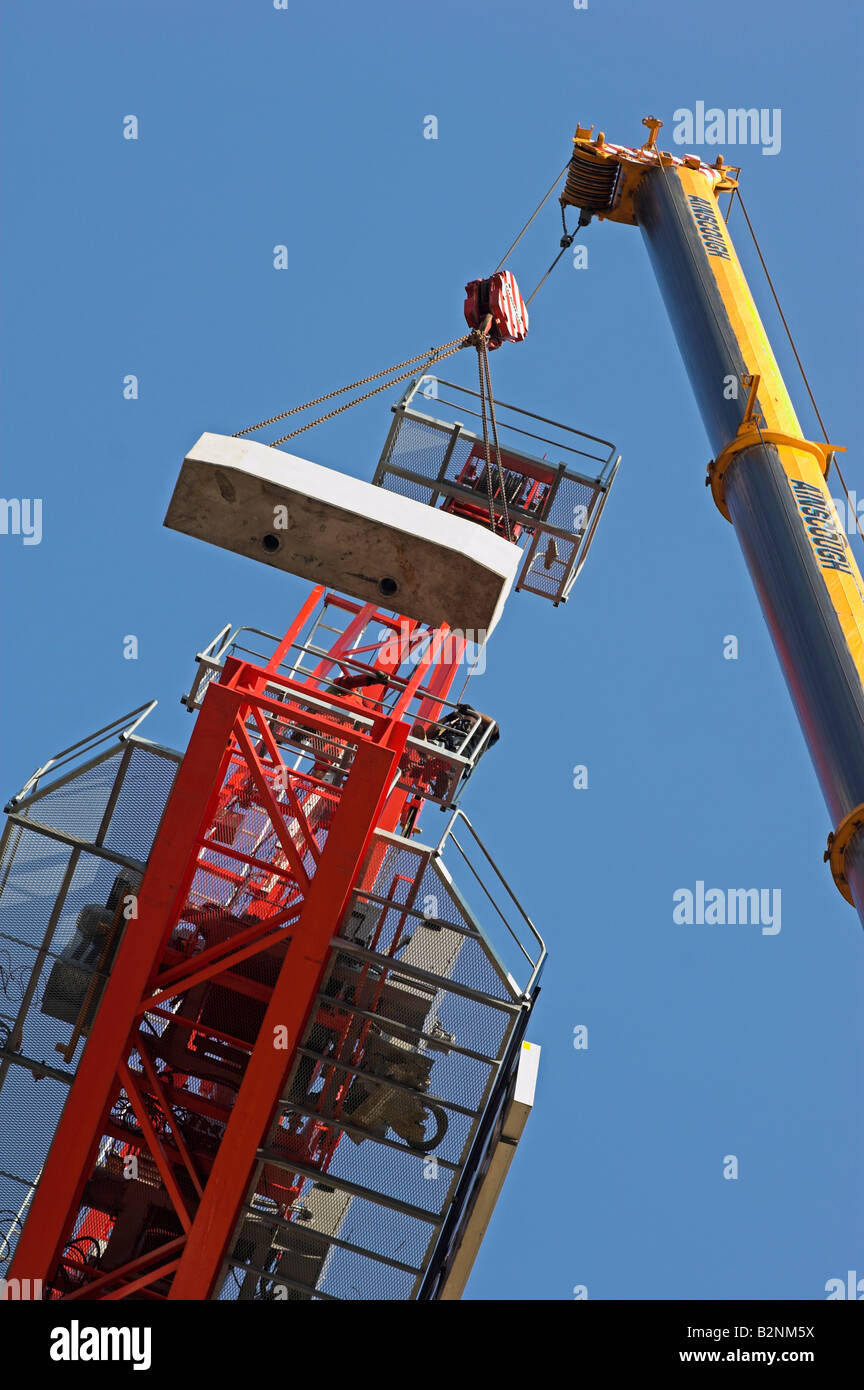 Hydraulic crane lifting concrete counterweight up to platform on tower crane UK Stock Photo