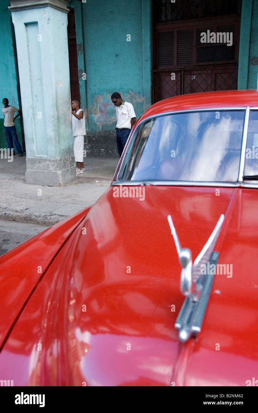 Overlooking a winged hood mascot of an old American vintage car towards people in the sidewalk in La Habana Vieja Havana Cuba Stock Photo
