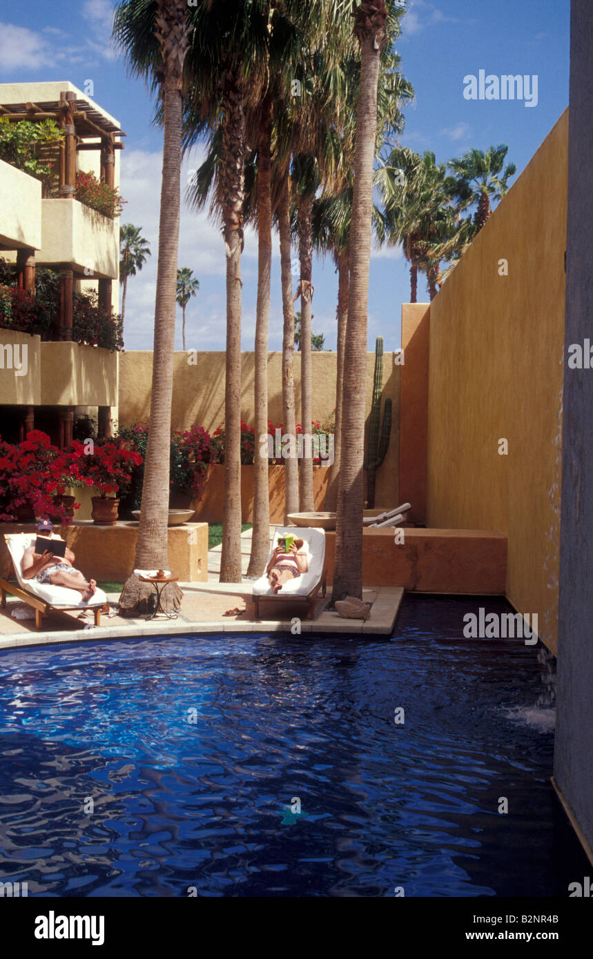 Tourists relaxing and reading books next to a hotel swimming pool in the town of San José del Cabo, Baja California, Sur Mexico Stock Photo
