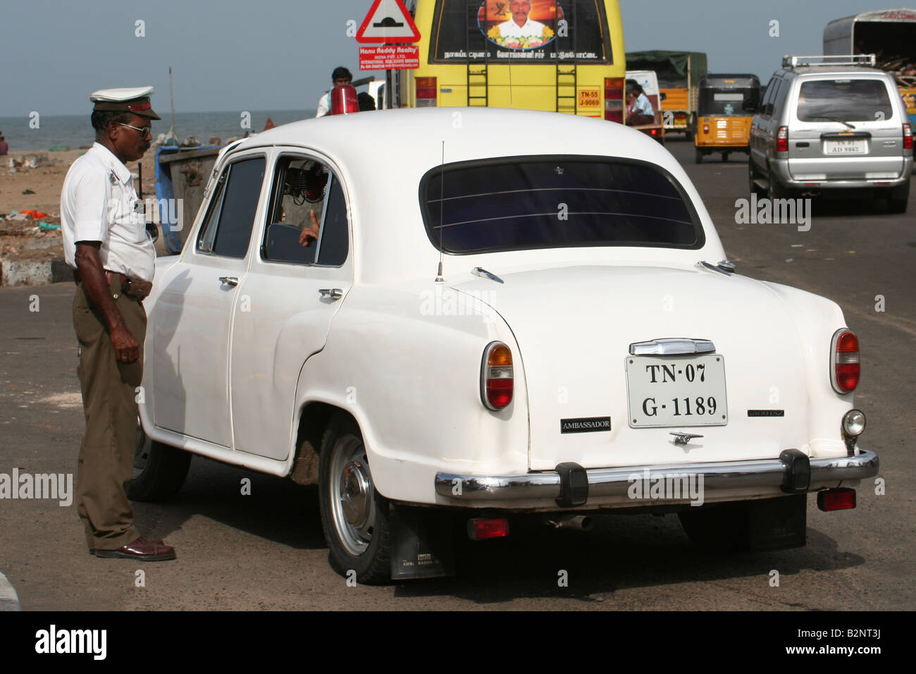 An Indian security guard checks an Ambassador car Stock Photo