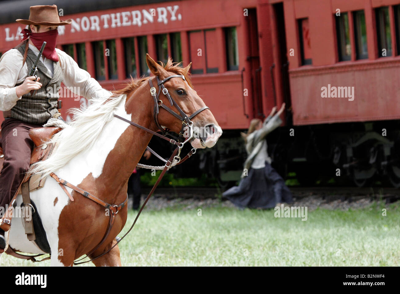 A cowboy bandit robbing an old steam train with a civilian girl trying to escape Stock Photo