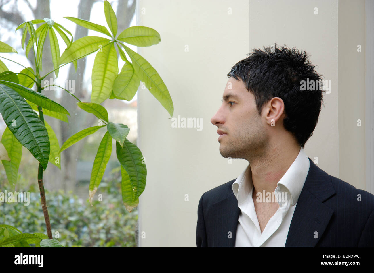 A young business man looking out of the window contemplating environmental issues, ESG investing and sustainable business models concept. Stock Photo