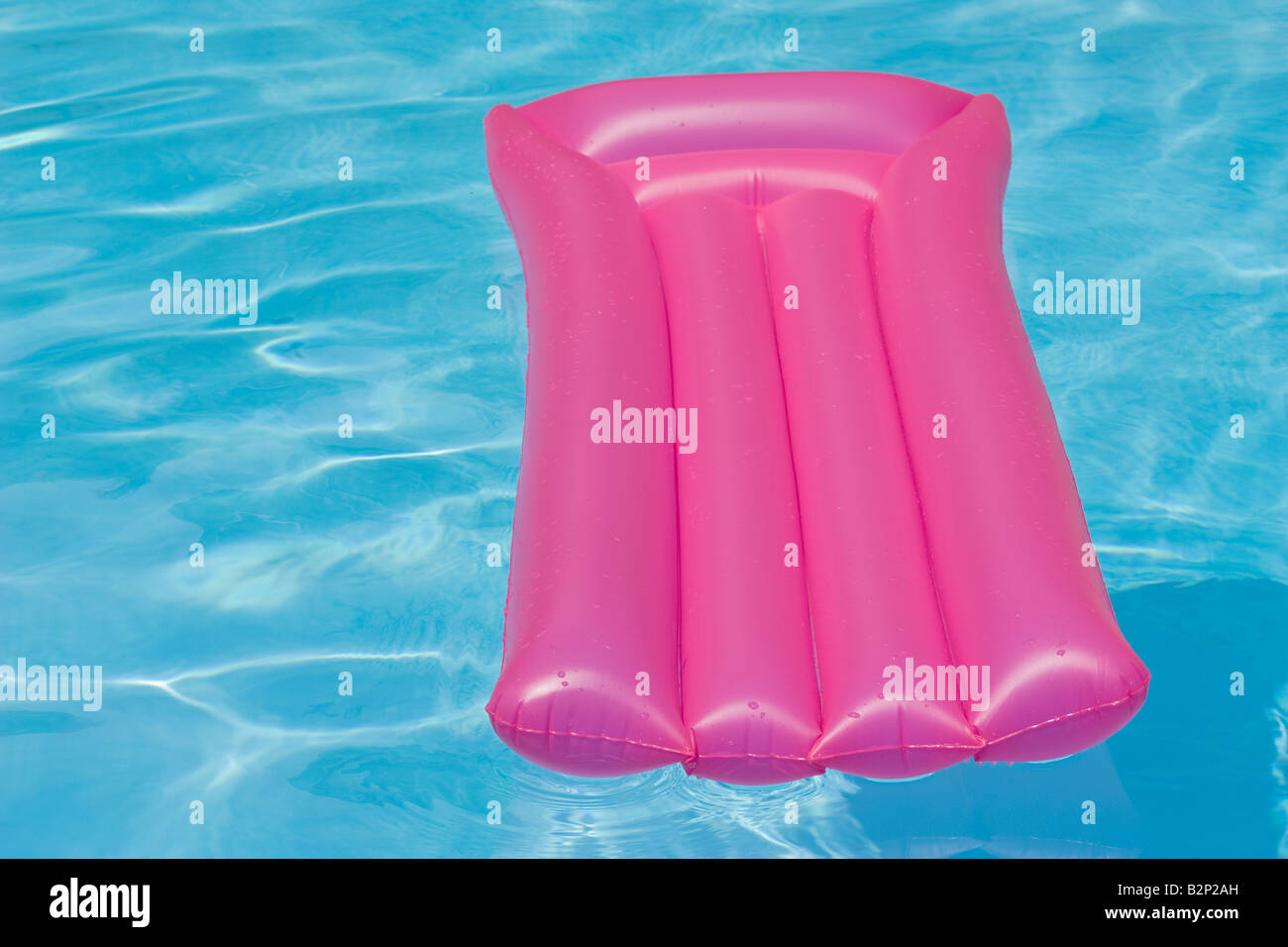 Pink inflatable chair floating in a swimming pool Stock Photo