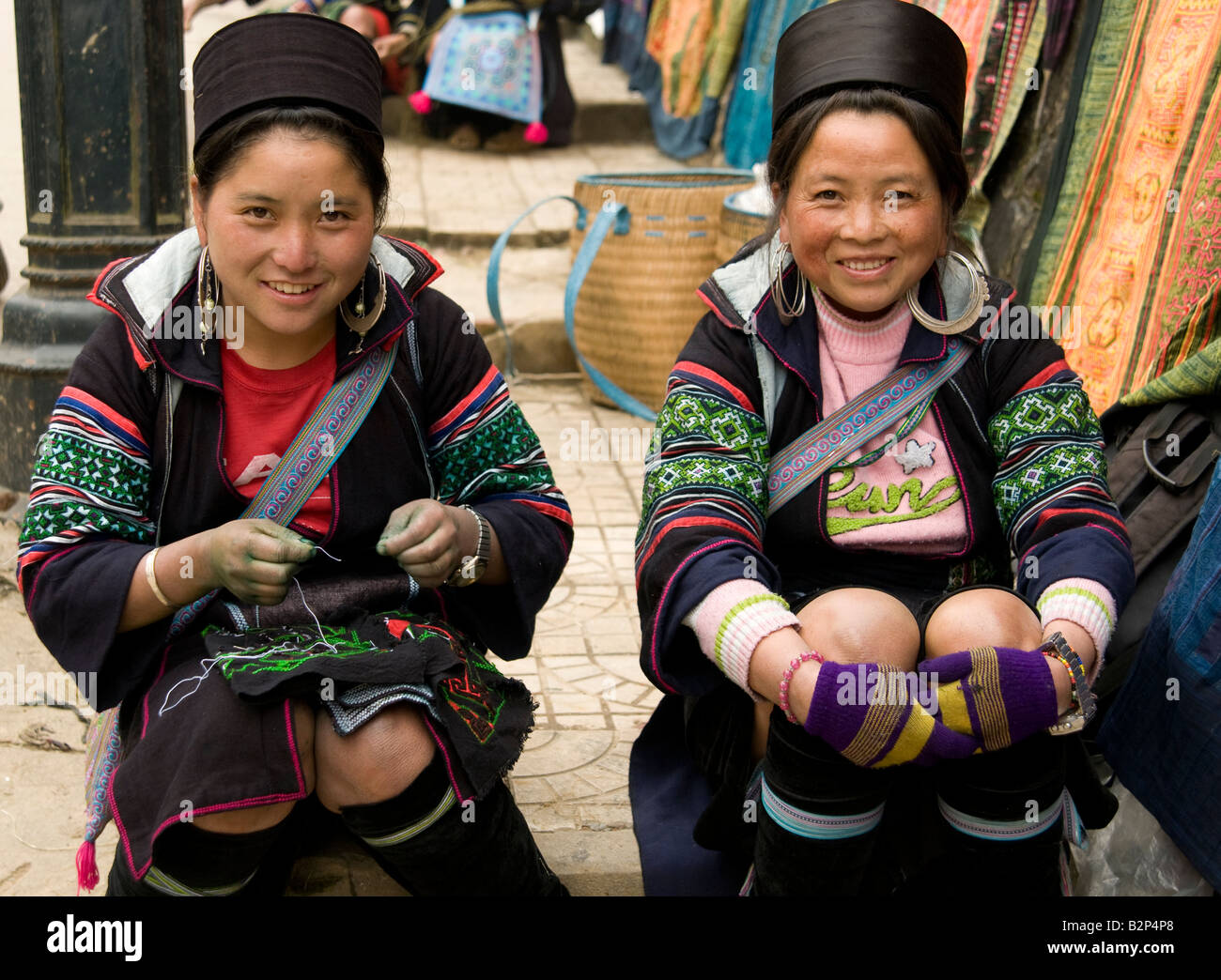 Two black Hmong tribe women wearing traditional costume smiling at the