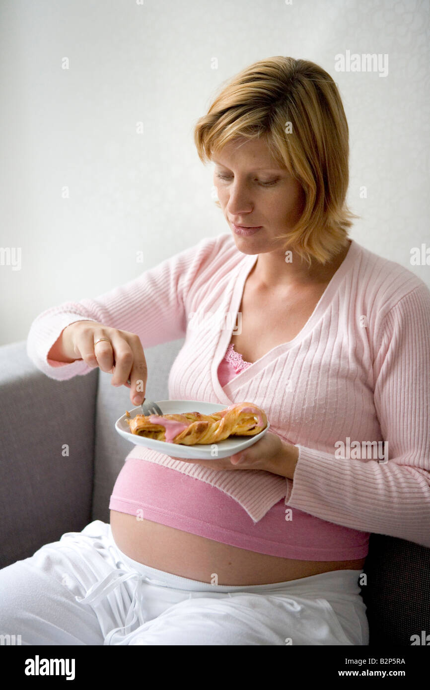 Pregnant woman eating cake Stock Photo