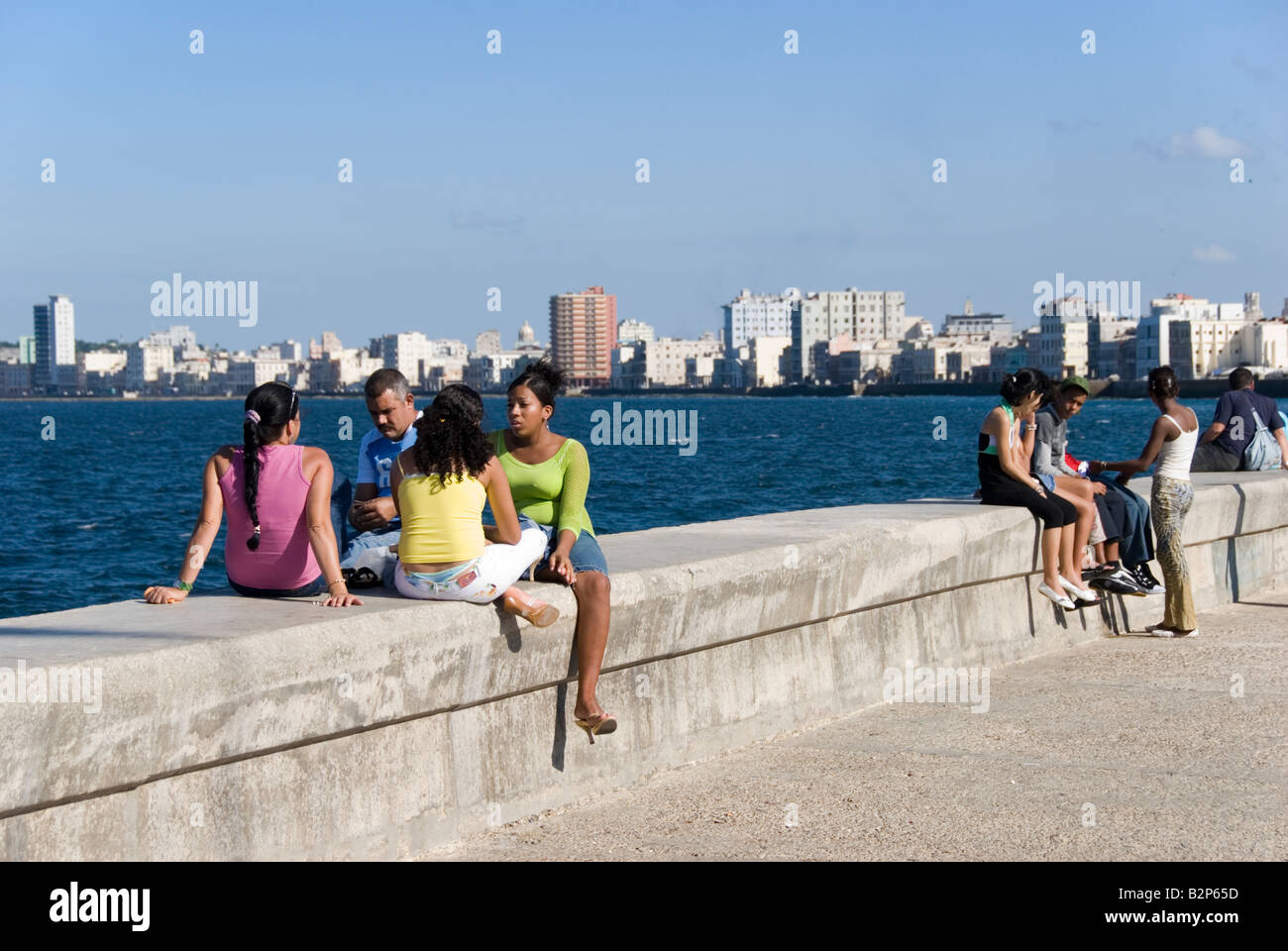 People sitting on sea wall on the El Malecon in Havana Cuba Stock Photo