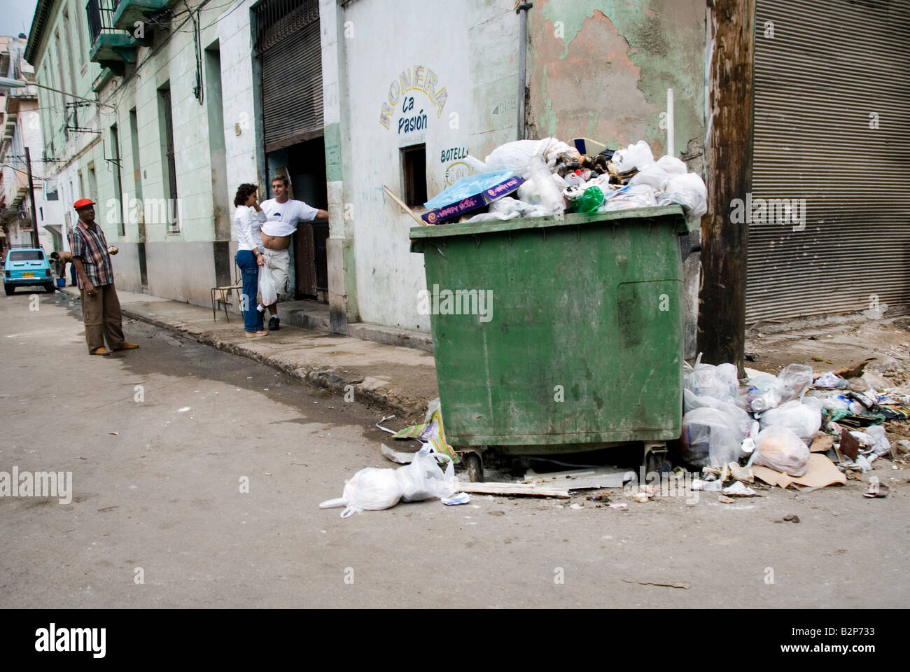 Street with overflowing rubbish bin in the run down Centro district during the time of embargo Central Havana Cuba Stock Photo